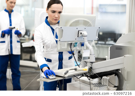 Research scientist in lab coat using modern equipment Research scientist in lab coat using modern equipment 63097216