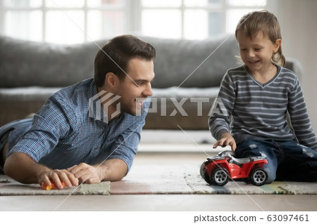 Joyful young father playing car toys with son. Joyful young father playing car toys with son. 63097461