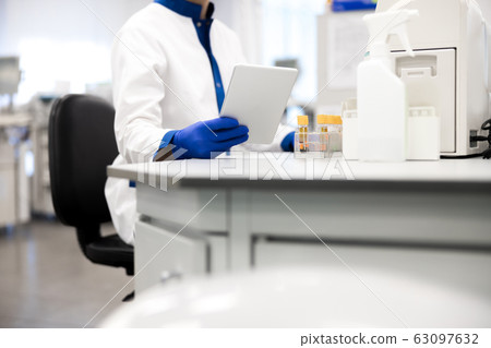Research scientist in sterile gloves holding digital tablet 63097632