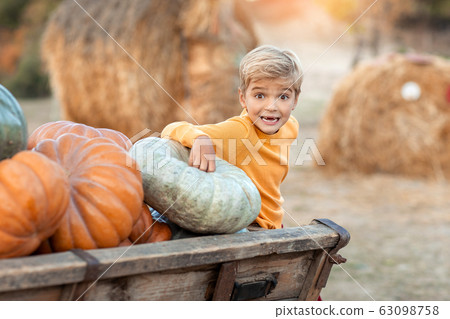 A baby in the fall stands and smiles on a farm near a pumpkin for Halloween A baby in the fall stands and smiles on a farm near a pumpkin for Halloween 63098758