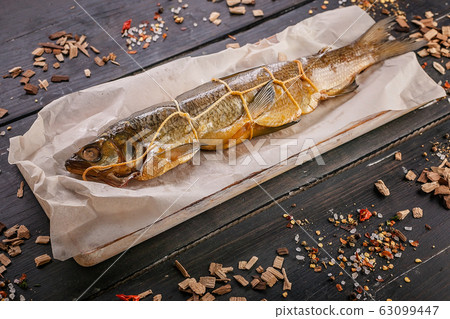 Appetizing hot smoked fish on a dark wooden background 63099447