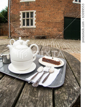 Tea set and cake on a round table on the terrace of a cafe in the suburbs of England 63099553