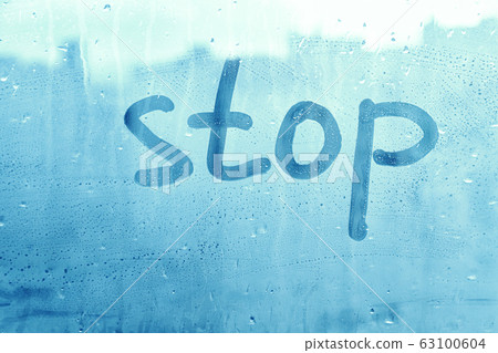 Foggy glass on window with written finger word blue color stop concept photo with copy space on blue background 63100604