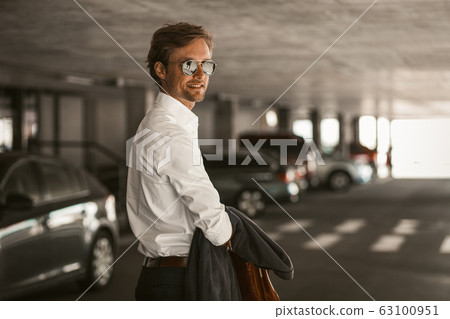Young businessman on the parking lot. Young businessman on the parking lot. 63100951