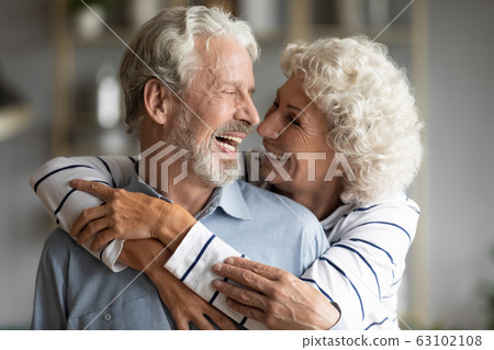 Happy elderly couple hug and cuddle sharing romantic moment Happy elderly couple hug and cuddle sharing romantic moment 63102108
