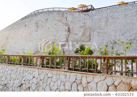 A light high stone wall with wooden rails 63102533