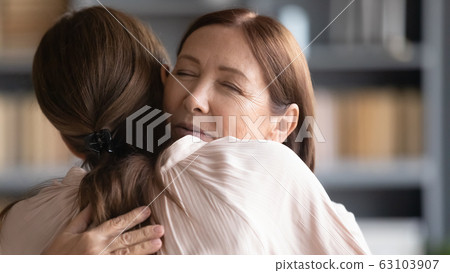 Affectionate middle aged mature woman embracing young daughter. 63103907
