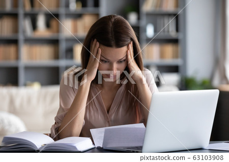 Stressed young woman holding head in hands, feeling desperate. 63103908