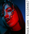 close up of a model looking at the camera with a chain in her mouth 63104467