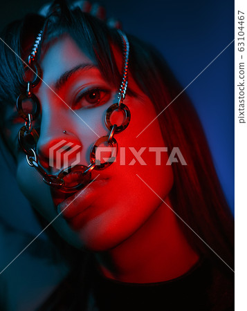 close up of a model looking at the camera with a chain in her mouth 63104467