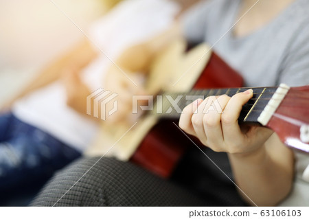 Young couple lover playing acoustic guitar on bedroom at home. Young couple lover playing acoustic guitar on bedroom at home. 63106103
