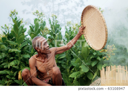 Old man holding a bamboo tray. Old man holding a bamboo tray. 63108947