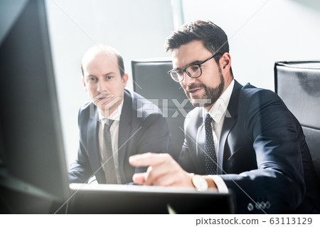 Business team analyzing data at business meeting in modern corporate office. Business team analyzing data at business meeting in modern corporate office. 63113129
