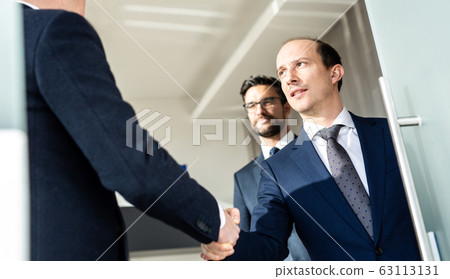 Group of confident business people greeting with a handshake at business meeting in modern office or closing the deal agreement by shaking hands. Group of confident business people greeting with a handshake at business meeting in modern office or closing the deal agreement by shaking hands. 63113131