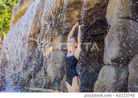 Young joyful woman under the water stream, pool, day spa, hot springs Young joyful woman under the water stream, pool, day spa, hot springs 63113748