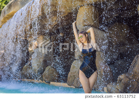 Young joyful woman under the water stream, pool, day spa, hot springs Young joyful woman under the water stream, pool, day spa, hot springs 63113752