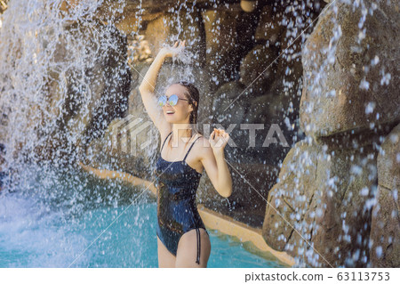 Young joyful woman under the water stream, pool, day spa, hot springs Young joyful woman under the water stream, pool, day spa, hot springs 63113753