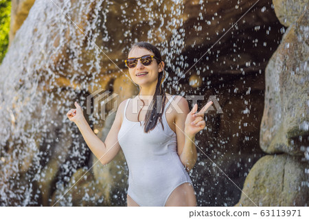 Young joyful woman under the water stream, pool, day spa, hot springs 63113971