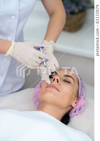 Cosmetologist wearing gloves doing mesotherapy for patient Cosmetologist wearing gloves doing mesotherapy for patient 63115679