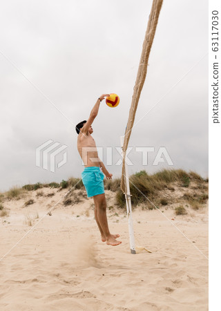 Young man playing volleyball on summer beach 63117030