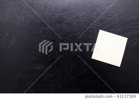 Stationery yellow stickers for inscription on a black leather isolated background. Blank sticker for reminder. Stationery yellow stickers for inscription on a black leather isolated background. Blank sticker for reminder. 63117389