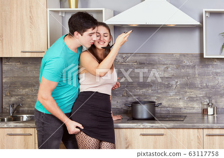 Young couple are tasting meal in kitchen. Young couple are tasting meal in kitchen. 63117758