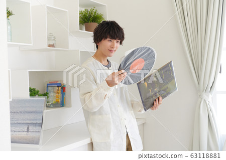 Young man looking at record jacket and record 63118881
