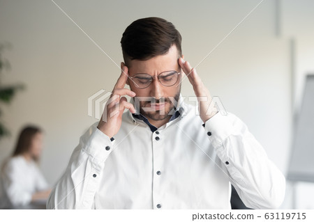 Stressed businessman suffering from strong sudden head ache. 63119715