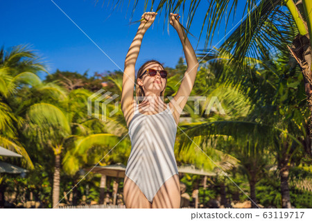 Young woman with the shadow of the palm leaf on her back. Relaxing on the seaside 63119717