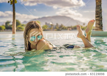 Luxury resort swimming pool. Beautiful woman tourist relaxing in holiday retreat on summer travel Luxury resort swimming pool. Beautiful woman tourist relaxing in holiday retreat on summer travel 63119898