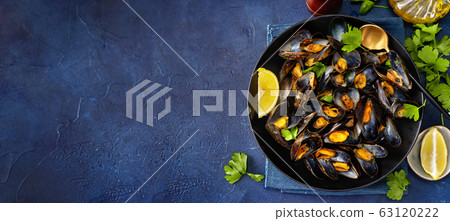 Flat lay of plate with cooked mussels with herbs 63120222