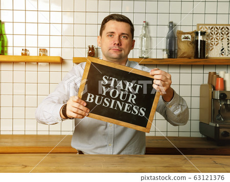 Businessman holds Start your small business sign. Businessman holds Start your small business sign. 63121376
