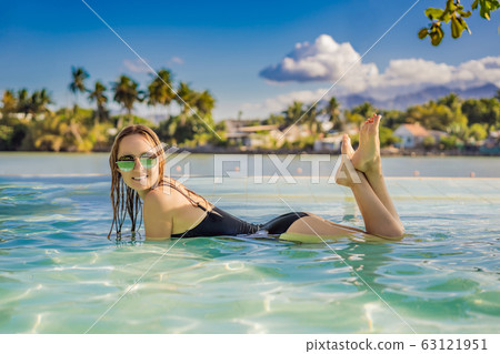 Luxury resort swimming pool. Beautiful woman tourist relaxing in holiday retreat on summer travel Luxury resort swimming pool. Beautiful woman tourist relaxing in holiday retreat on summer travel 63121951