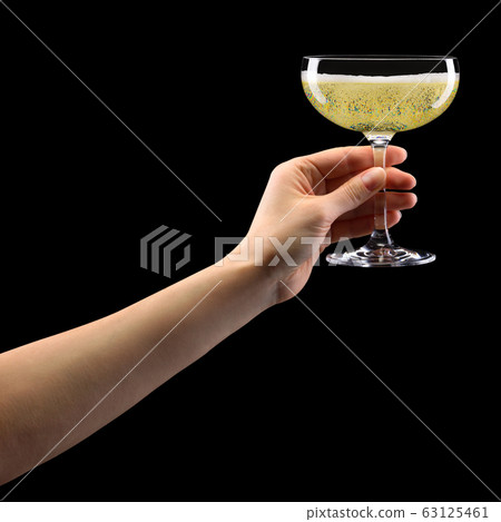 Woman hand holding glass of sparkling champagne isolated on black. 63125461