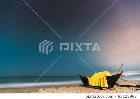 Goa, India. Real Night Sky Stars. Natural Starry Sky Blue Color Above Sea Seascape Ocean Beach. Background. Parked Old Wooden Boat At Coast 63125968