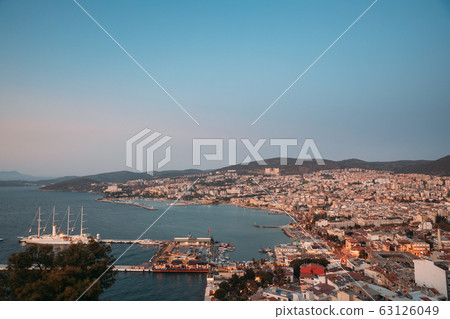 Kusadasi, Aydin Province, Turkey. Waterfront And Kusadasi Cityscape In Summer Evening. Scenic View Of Kusadasi Skyline At Aegean Coast, Turkey Kusadasi, Aydin Province, Turkey. Waterfront And Kusadasi Cityscape In Summer Evening. Scenic View Of Kusadasi Skyline At Aegean Coast, Turkey 63126049