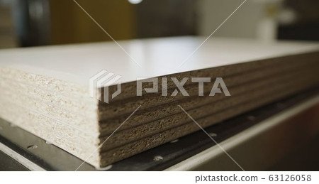 Worker with boards in a factory. The young master folds the board. Dvp production. Cutting sheets of wood chipboard material. 63126058