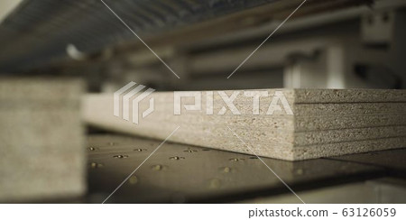 Worker with boards in a factory. The young master folds the board. Dvp production. Cutting sheets of wood chipboard material. 63126059