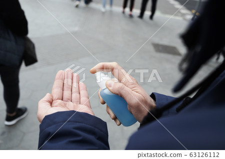 man disinfecting his hands with hand sanitizer 63126112