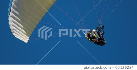 Paraglider tandem fly against the blue sky, tandem paragliding guided by a pilot 63126284
