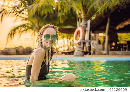 Luxury resort swimming pool. Beautiful woman tourist relaxing in holiday retreat on summer travel Luxury resort swimming pool. Beautiful woman tourist relaxing in holiday retreat on summer travel 63126609
