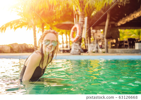 Luxury resort swimming pool. Beautiful woman tourist relaxing in holiday retreat on summer travel Luxury resort swimming pool. Beautiful woman tourist relaxing in holiday retreat on summer travel 63126668