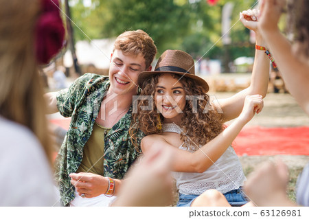 Group of young friends sitting on ground at summer festival. Group of young friends sitting on ground at summer festival. 63126981