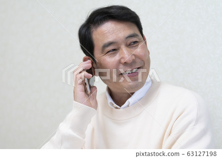 一個五十多歲的男人在智能手機上聊天。 63127198