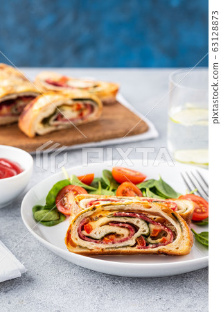 Italian food Pizza roll stromboli with cheese, salami, spinach and red pepper a light background. 63128873