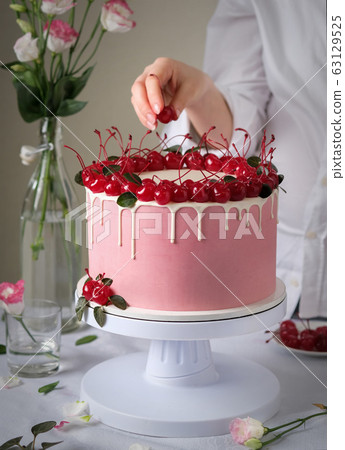 Cake with cherry. The confectioner decorates the cake. 63129525