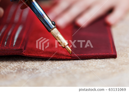 A leather craftsman works with leather. Sews A leather craftsman works with leather. Sews 63131069