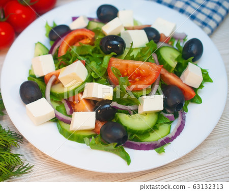 Greek salad with tomatoes, cucumbers and feta cheese with olives on the table 63132313