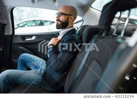 Man checks the comfort of rear seats in automobile 63133234