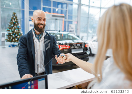 Man takes the key from new auto in car dealership 63133243